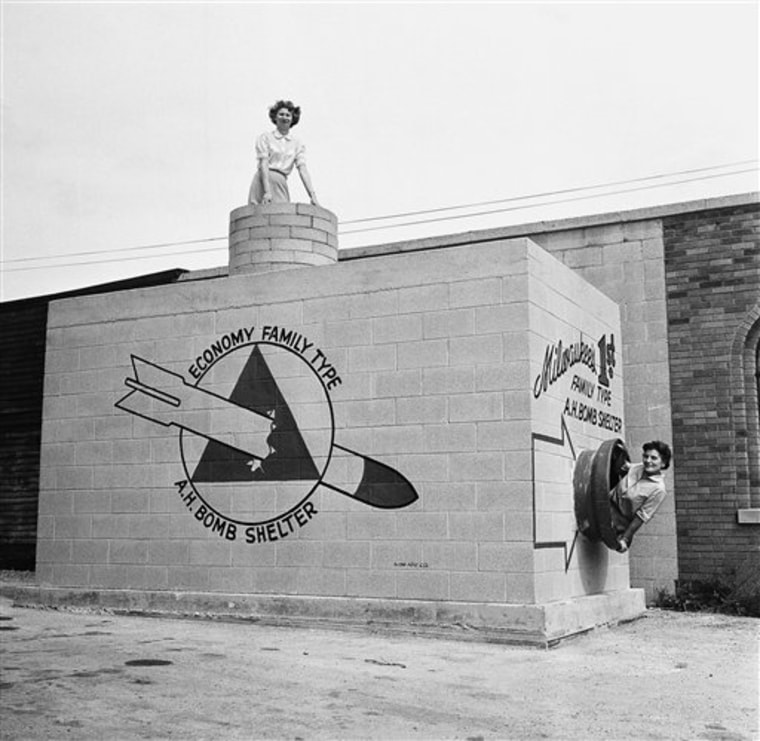FILE - In this Sept. 12, 1958 file picture, Beverly Wysocki, top, and Marie Graskamp, right, emerge from a new family-type bomb shelter on display in Milwaukee, Wis. Even before the March 11 earthquake and resulting tsunami that led to the current Japanese nuclear crisis, Americans were bombarded with contradictory images and messages that frighten even when they try to reassure. It started with the awesome and deadly mushroom cloud rising from the atomic bomb, which led to fallout shelters and school duck-and-cover drills. (AP Photo/File)